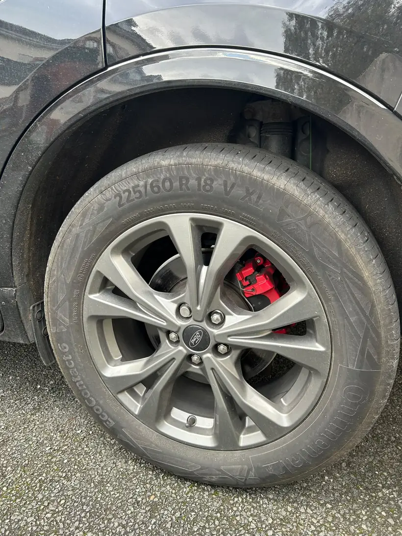 The wheel back on after the brake replacement, red caliper behind the spokes