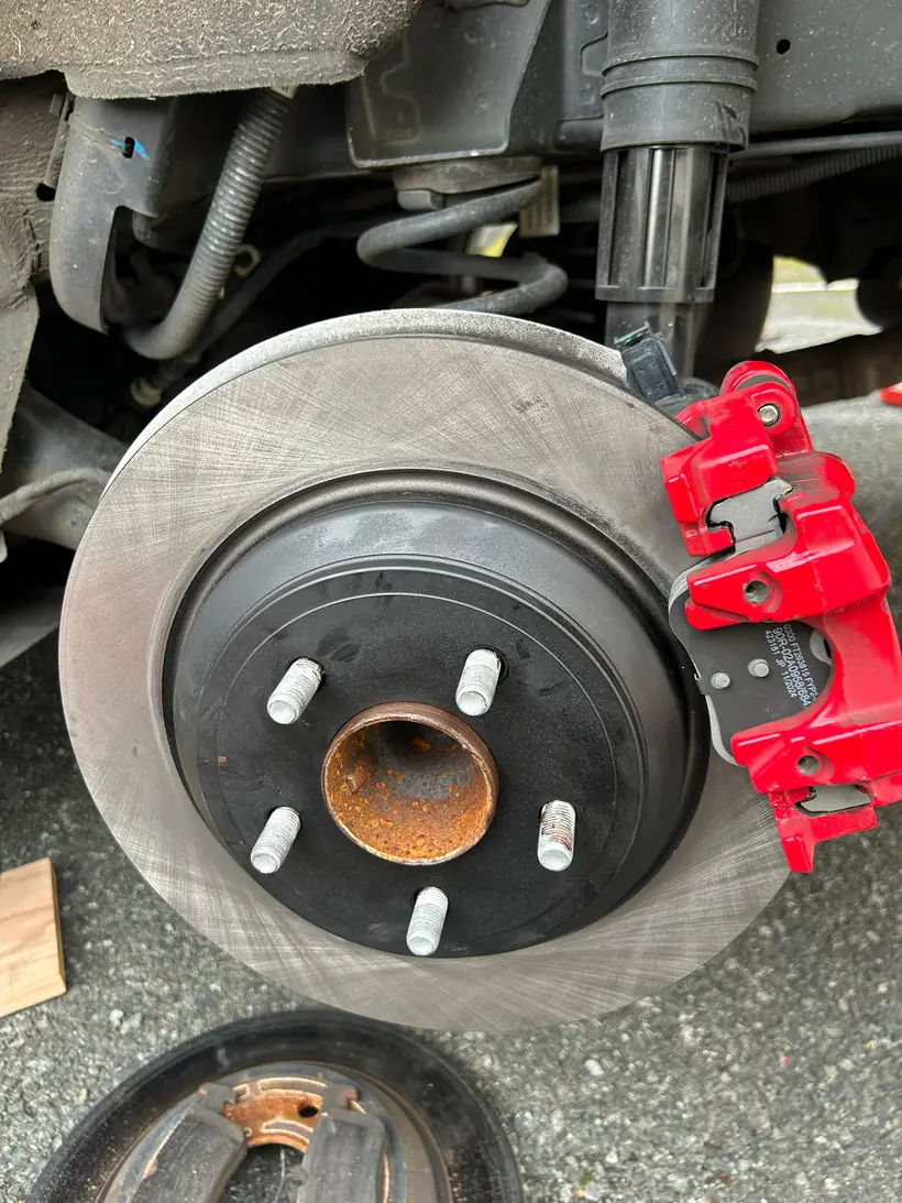 Close-up of a new brake disc behind a red caliper, fitted at the customer's home