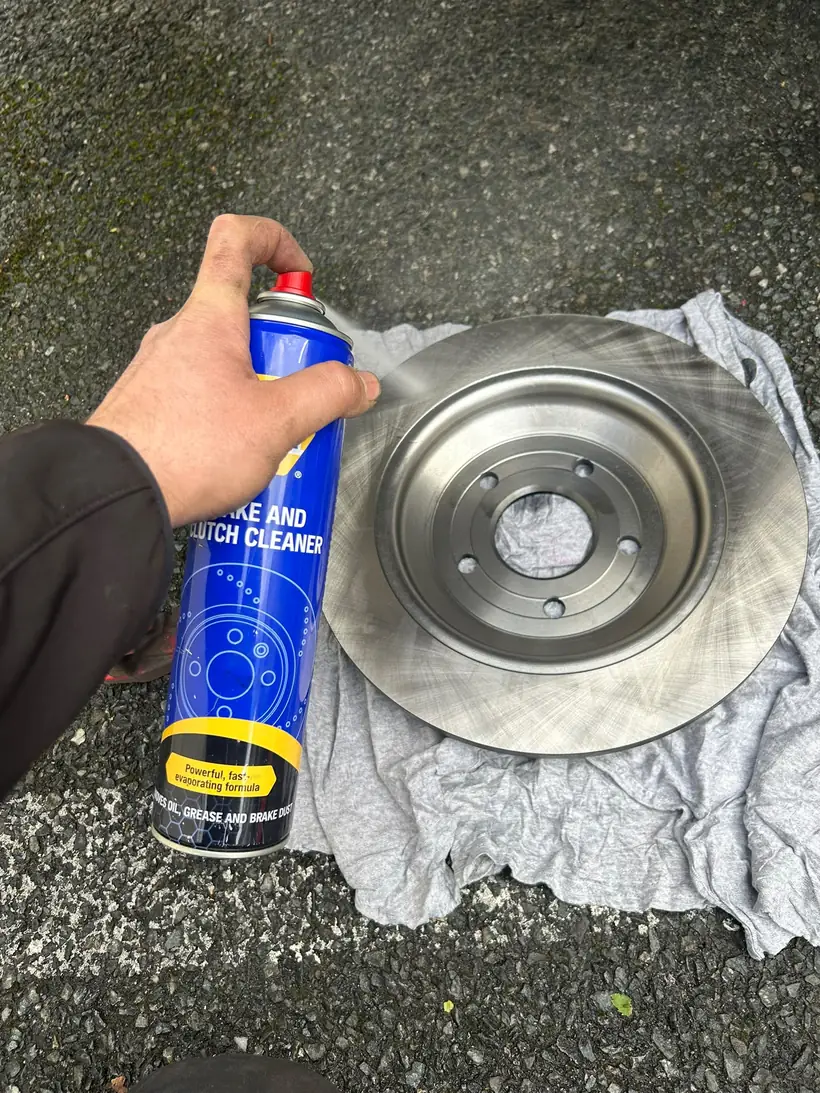 Cleaning a new brake disc with brake cleaner before it goes on the car