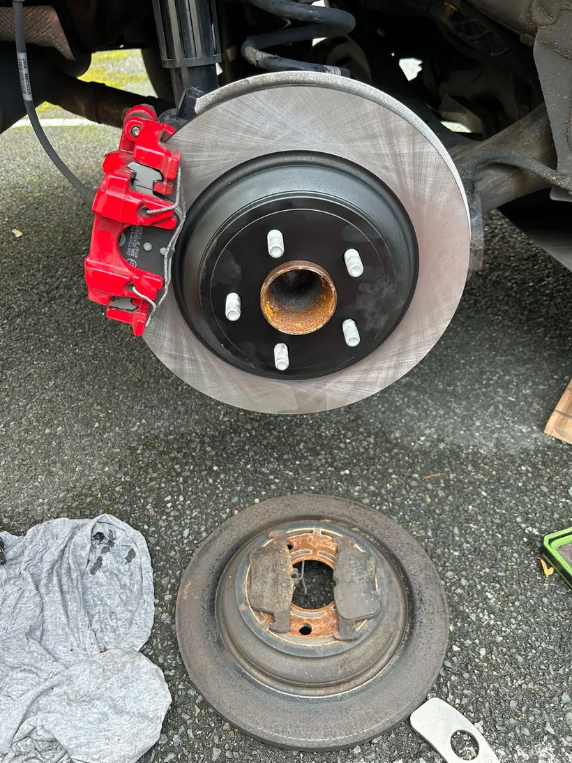 New rear disc and caliper fitted, the worn disc and old brake pads on the ground
