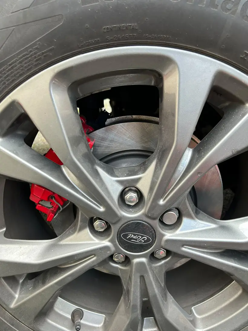 Alloy wheel and red brake caliper, close up, after a mobile brake job