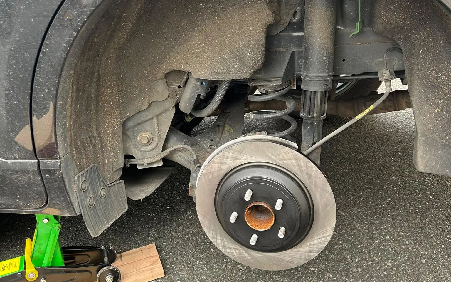 Rear brake replacement at home in Dublin: new disc on the hub, wheel off, car on a jack in the driveway